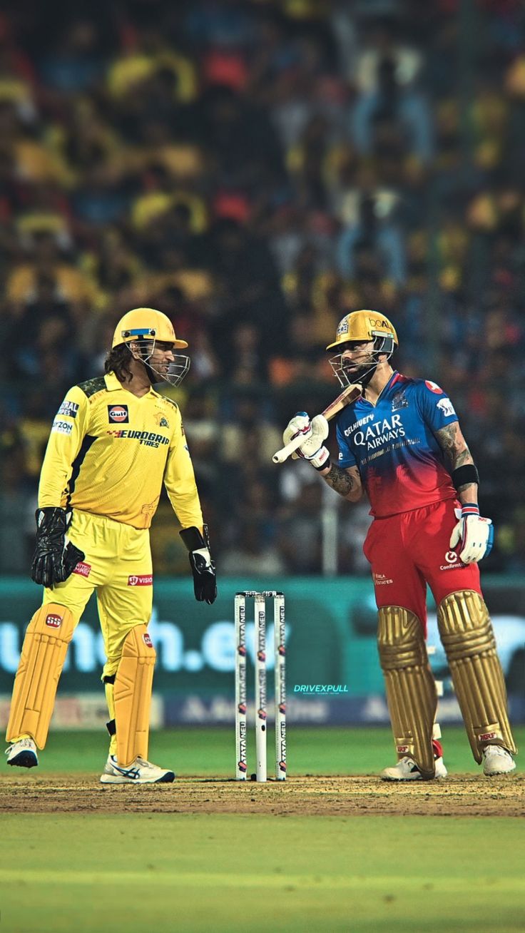 two men in yellow and red uniforms standing on a field next to a cricket ball