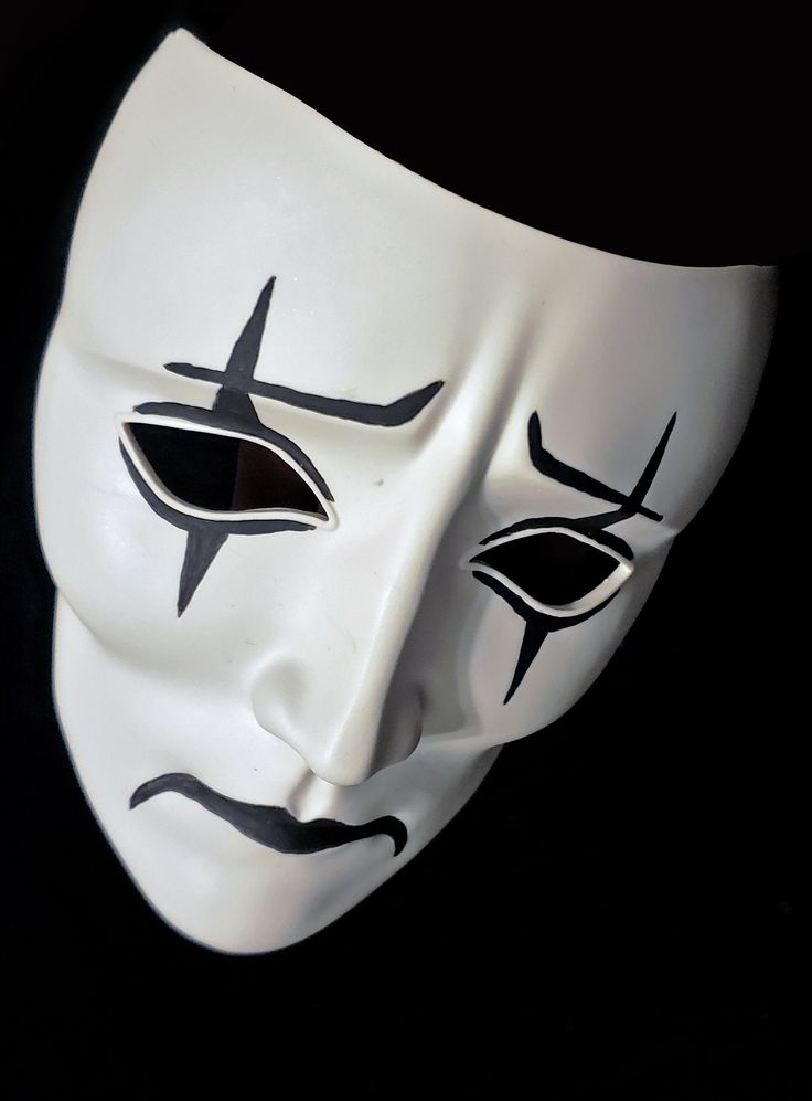 a white mask with black lines painted on it's face and eyes, against a black background