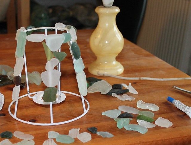 sea glass on a wooden table next to a lamp and other items that are broken