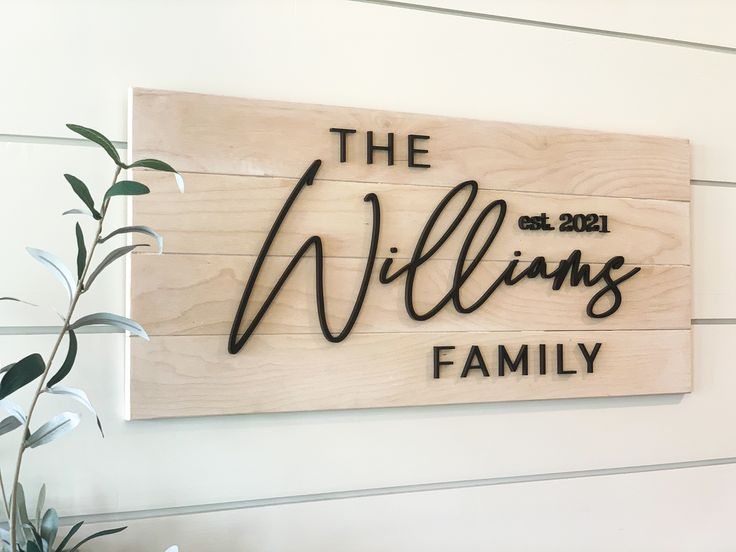 a wooden sign that says the williams family on it's side, next to a potted plant