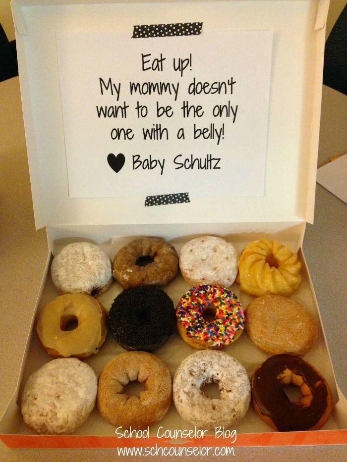 an open box filled with lots of donuts on top of a wooden table next to a sign