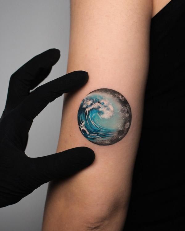 a woman's arm with a blue and white wave tattoo on it