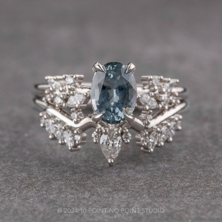 a blue and white diamond ring sitting on top of a gray surface with diamonds around it