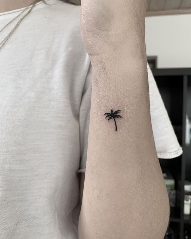 a small palm tree tattoo on the arm