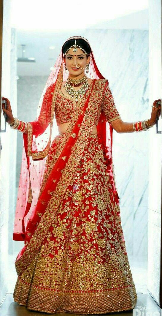 a woman in a red and gold bridal gown with her hands on her hips