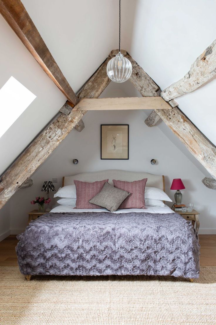 a bed in a room with wooden beams on the ceiling and pillows on the bed