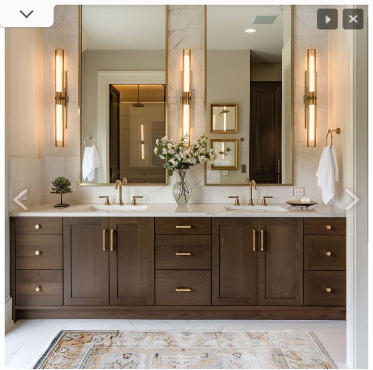 a bathroom with two sinks, mirrors and lights on the wall in front of it