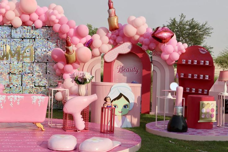 a pink and white birthday party setting with balloons, decorations, and toys on the lawn