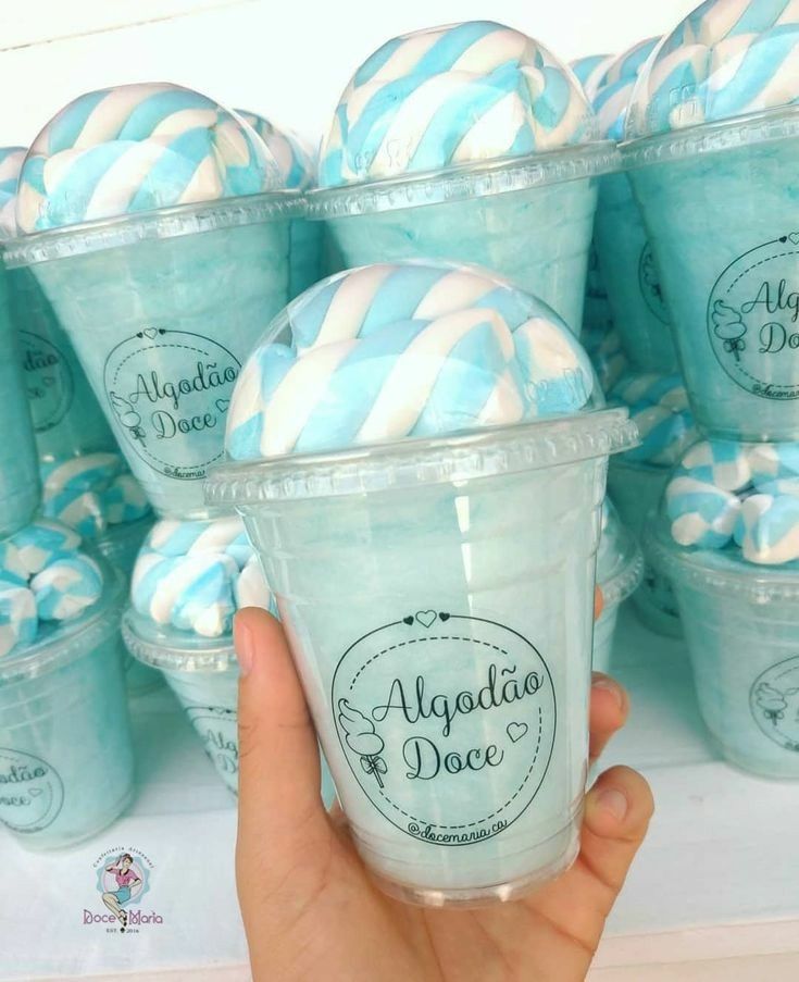 a hand is holding up a cup with blue and white striped straws in it