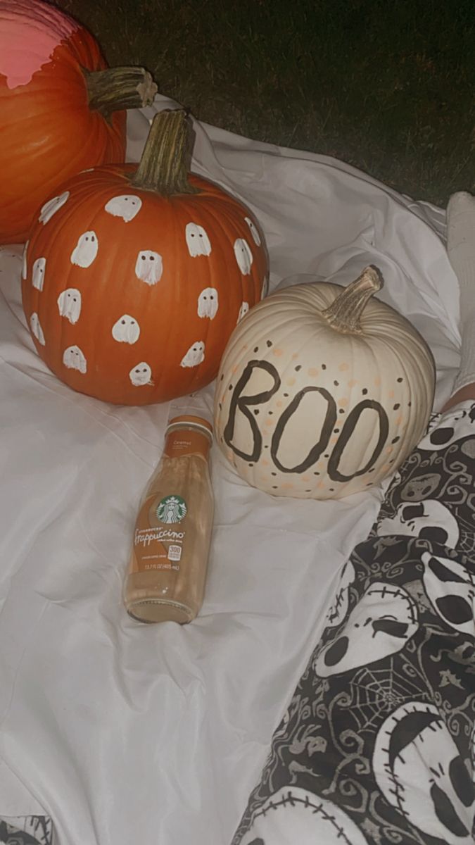 pumpkins and other decorative items sitting on a bed with the word boo written on them