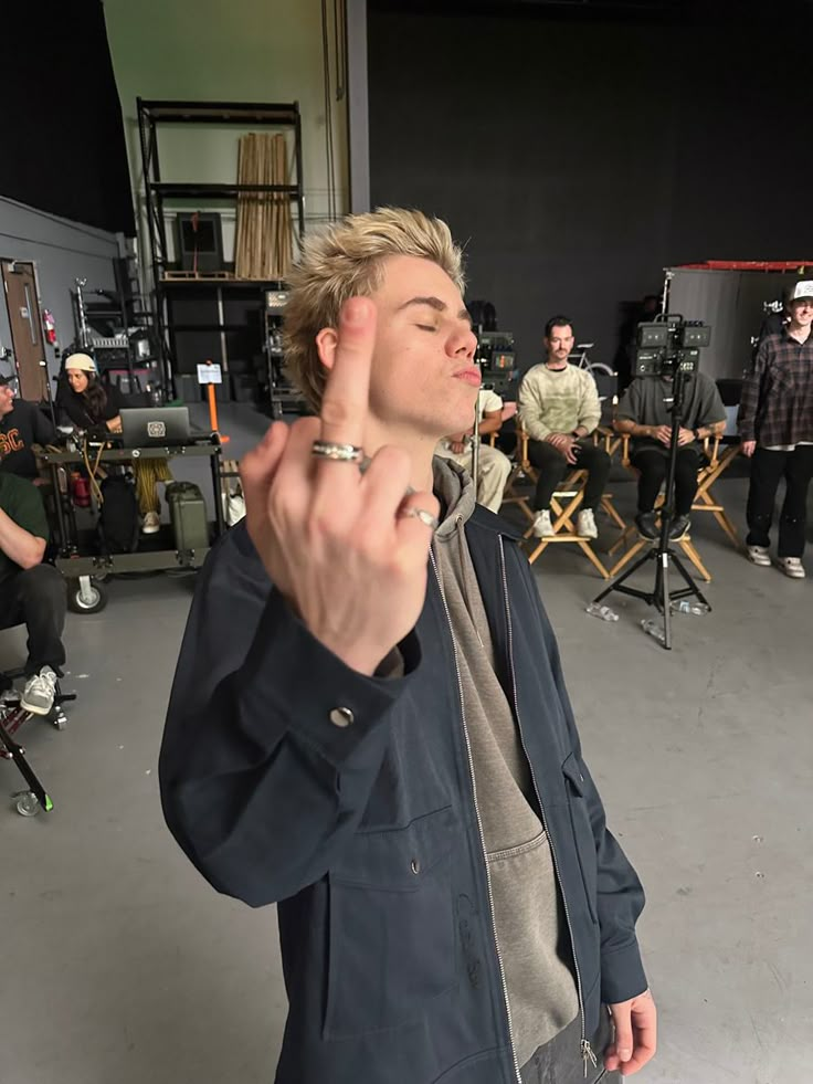 a man in a recording studio pointing to the side with his finger on his face