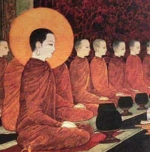 a group of monks sitting on the ground in front of each other with orange hats