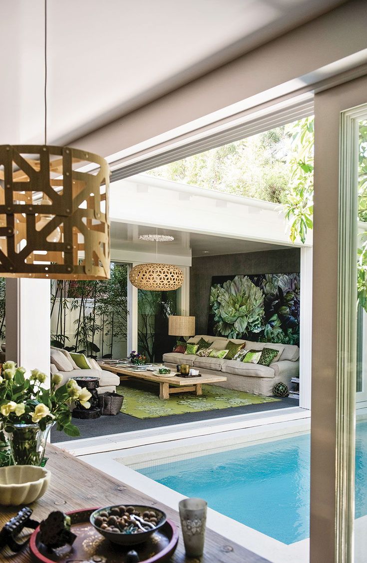 a living room with a pool and outdoor furniture in the back yard, as well as an open patio area