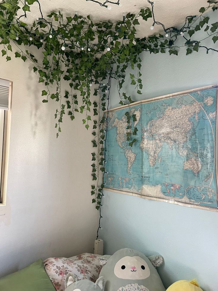 a stuffed animal sitting on top of a bed under a green plant hanging from the ceiling