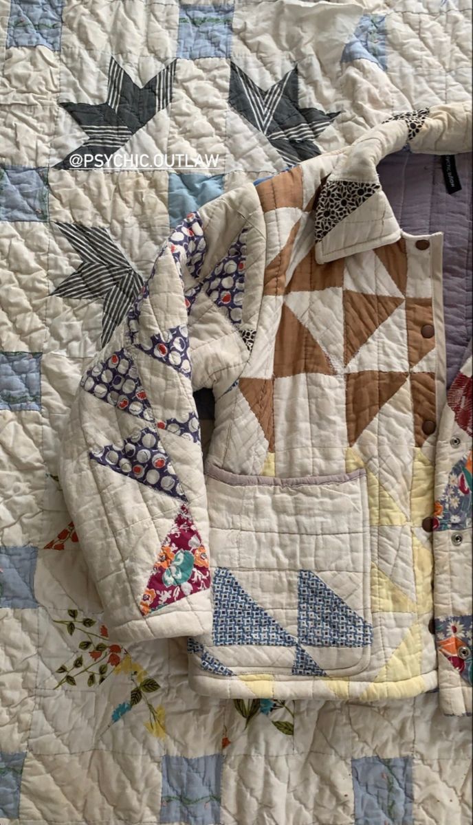 an old quilt is laying on top of a bed with two jackets hanging from it's sides