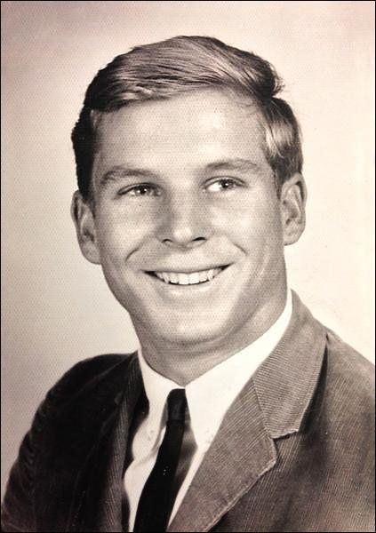 a man in a suit and tie smiling at the camera