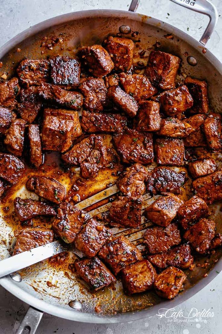 meat being cooked in a pan with tongs