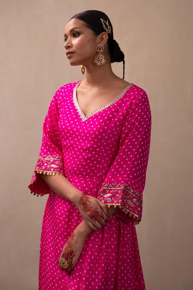 Hot pink silk A-line kurta with all over bandhani pattern, side lacing tie-ups, zardozi embroidered bell sleeves border and leaf neck. Paired with straight fit pant with embroidered border. Components: 2 Pattern: Embroidered Type Of Work: Bandhani Pattern and Zardozi Work Neckline: Leaf Neck Sleeve Type: Bell Sleeves Fabric: Silk Color: Pink Other Details:  Drop tassel details Kurta Closure: Side lacing tie-ups Occasion: Sangeet,Mehendi and Haldi - Aza Fashions Bandhani Suit Design, Bell Sleeves Suit, Bandhej Kurti Designs, Bandhani Suits Design, Cotton Bandhani Dress Pattern, Sleves Desine Kurti, Bandhani Dress Design, Hot Pink Kurti, Bandhani Outfit Ideas