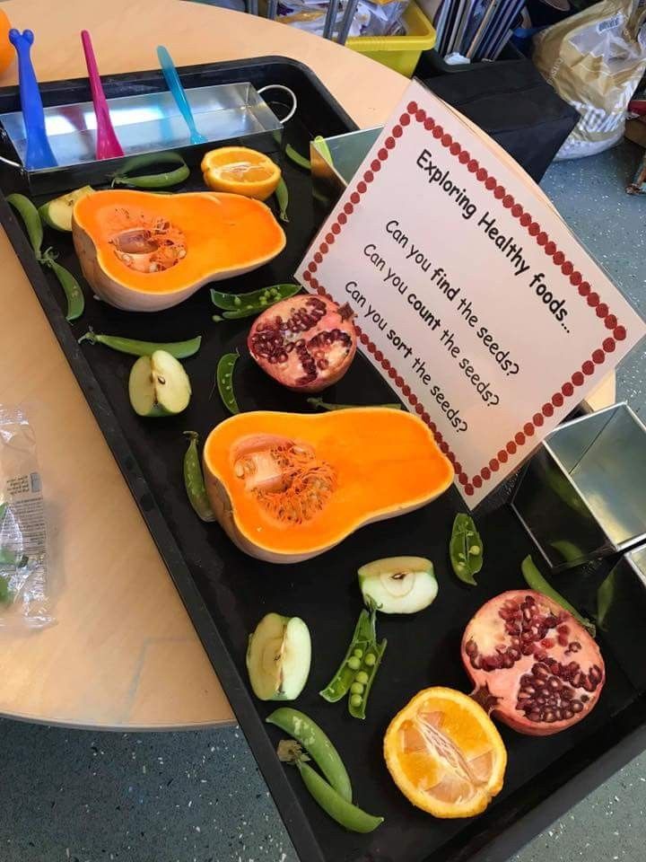 a tray filled with cut up fruit on top of a table next to a sign