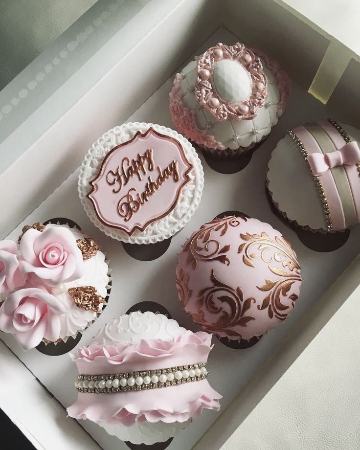 pink and white decorated cupcakes in a box