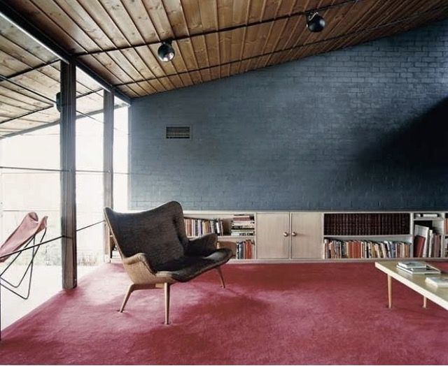 a living room filled with furniture and bookshelves next to a red carpeted floor