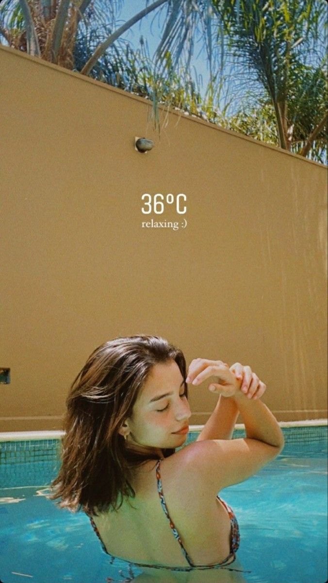 a woman in a swimming pool with palm trees and a sign above her that says cafe cancuaca