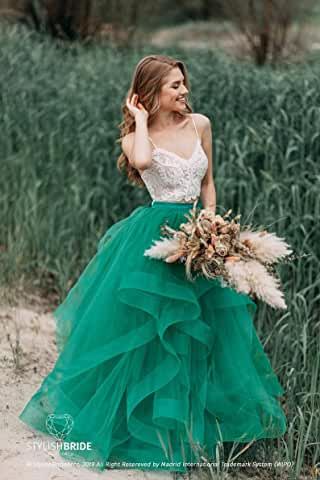 a woman in a green dress is standing by some tall grass and holding a bouquet