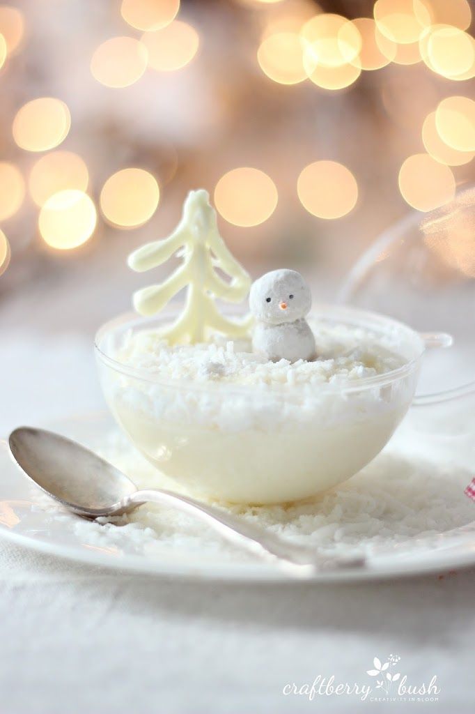 a white plate topped with a bowl filled with snow and a small figurine