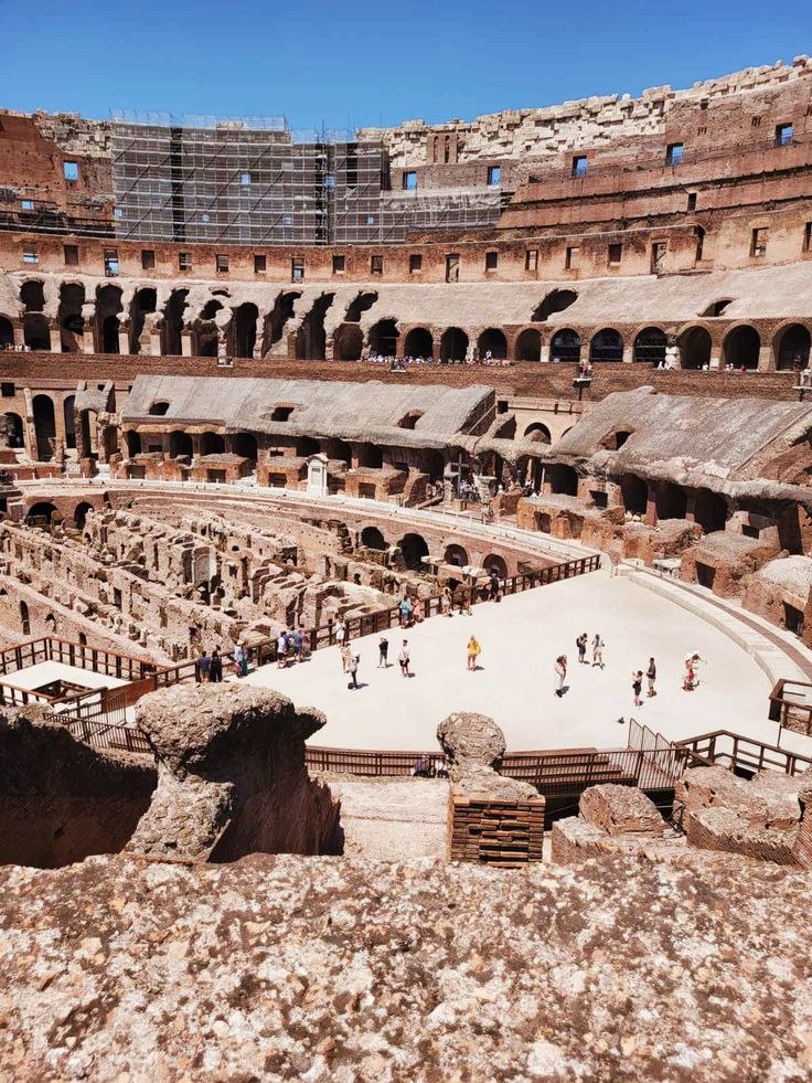 the interior of an old roman amphite with people walking around and sitting on benches