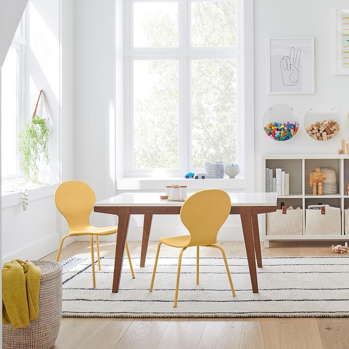 a dining room with yellow chairs and a white table in front of a large window