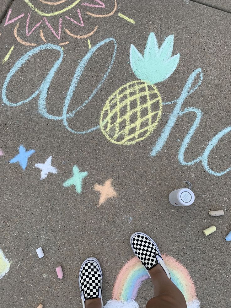 someone standing on the sidewalk with their feet in front of chalk writing and pineapples