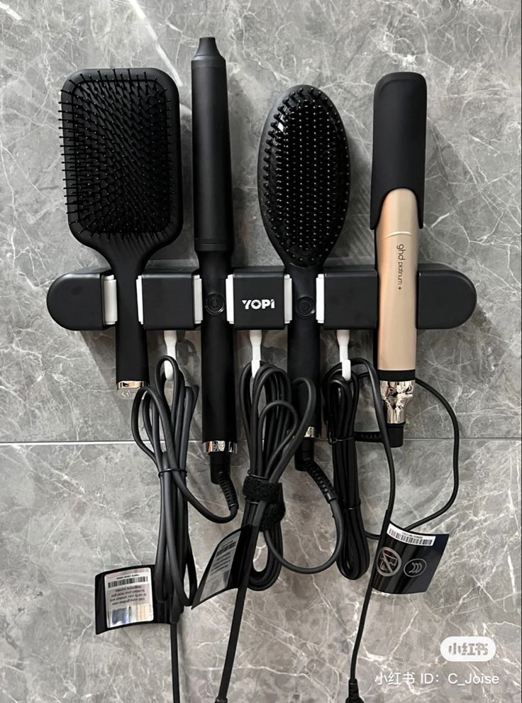 there are many hairbrushes on the wall with cords attached to it and plugged in