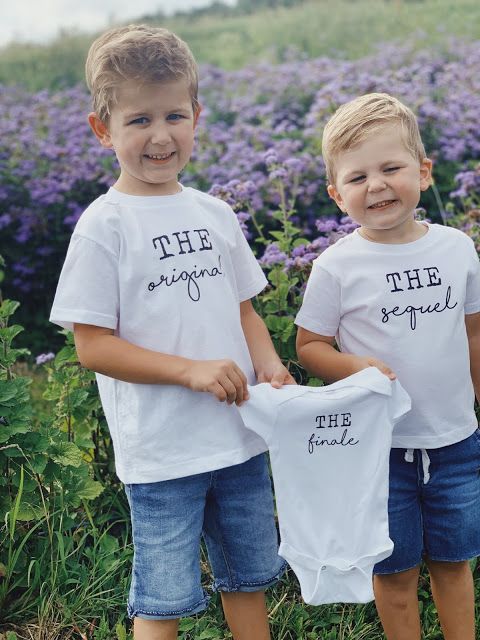 two young boys standing next to each other holding shirts