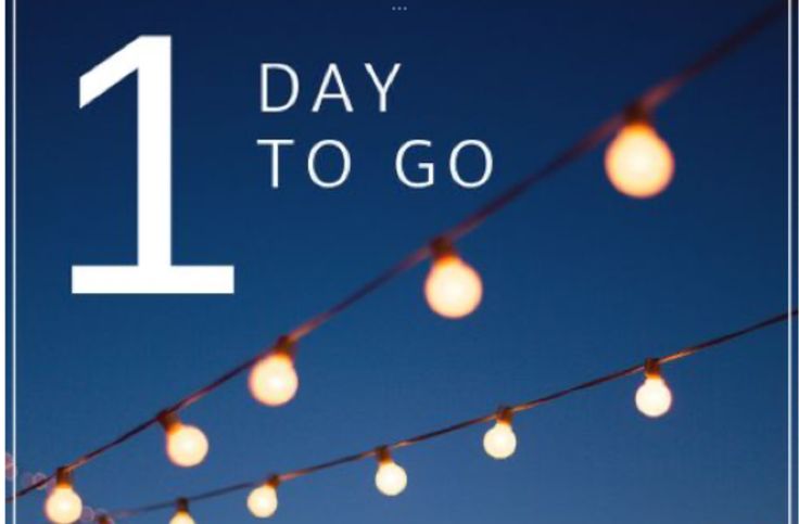 the number one day to go sign is lit up with string lights and blue sky in the background