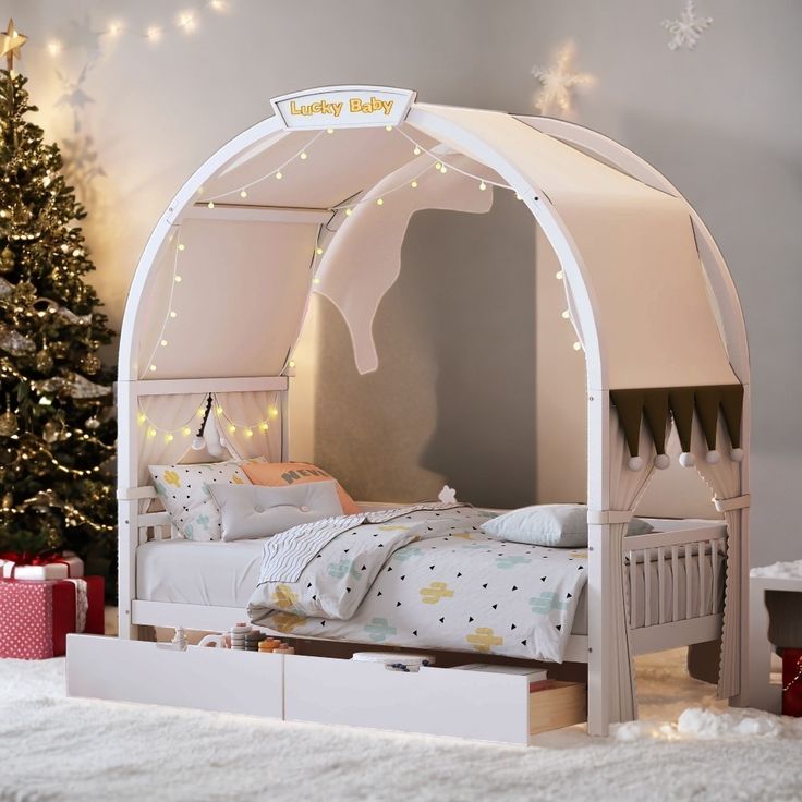 a white bed sitting under a christmas tree next to a small child's bed