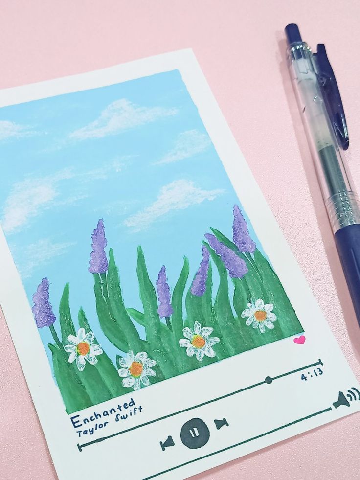 a drawing of flowers and grass on a pink surface with a blue ballpoint pen