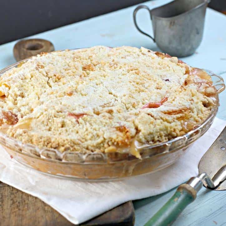 a pie sitting on top of a wooden table next to a knife and fork in front of it