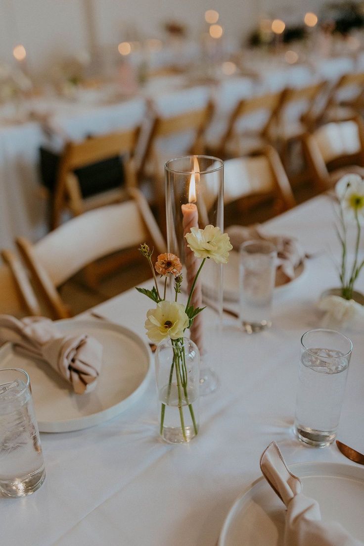 the table is set with plates, silverware and flowers in vases on it