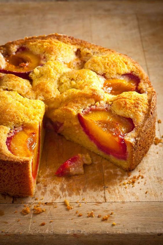 a peach cobbler is cut into pieces on a cutting board with one slice missing