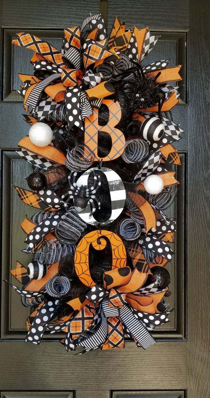 an orange and black wreath with the letter b on it is hanging on a door