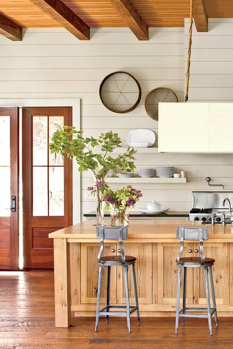 a kitchen with two stools and an island in front of the counter top that has plants on it