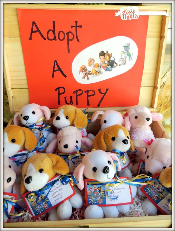 there are many stuffed animals in the box with an adopt a puppy sign on it