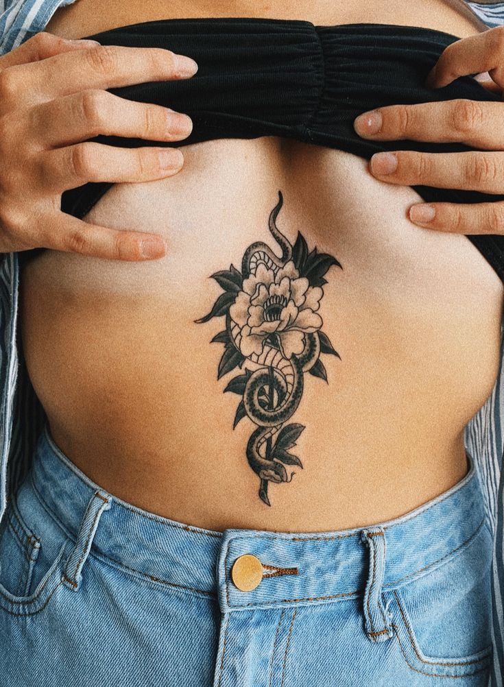 a woman's stomach with a flower tattoo on her belly and the bottom part of her lower back