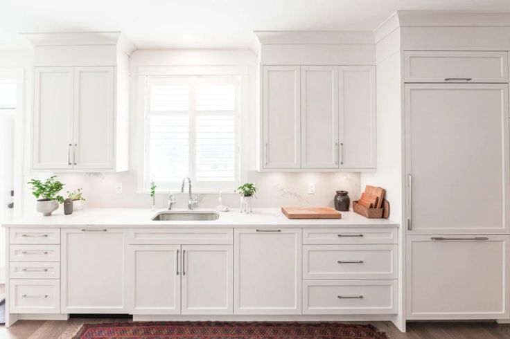 a kitchen with white cabinets and an area rug in front of the counter top that matches the floor