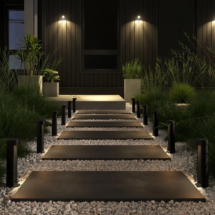 a set of steps lit up by lights in front of a building with grass and plants