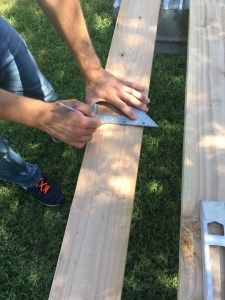 a man sanding wood with a saw on the ground next to another person's hand