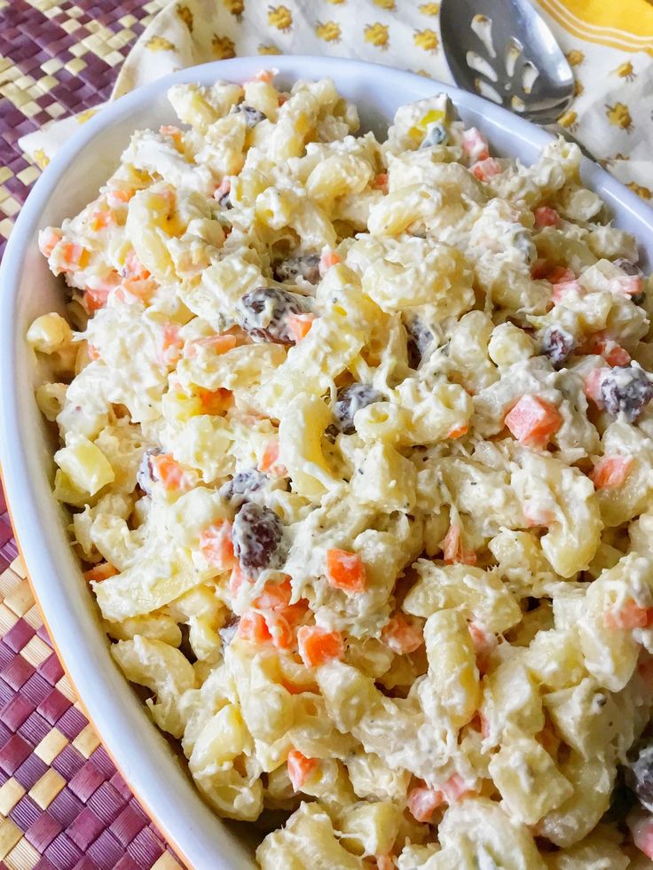 a white bowl filled with macaroni salad on top of a purple and yellow table cloth