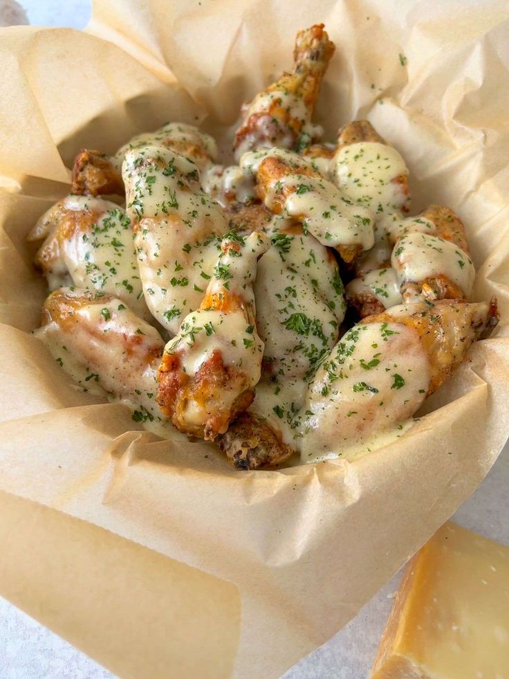 a bowl filled with chicken sitting on top of a table next to slices of cheese