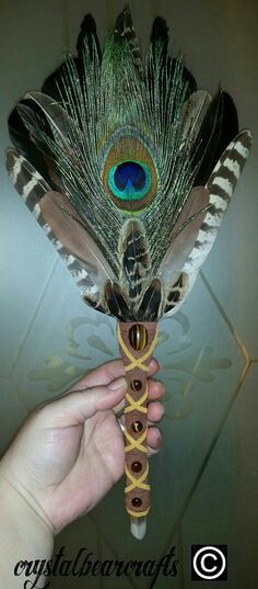 a person holding a peacock feather on top of a stick