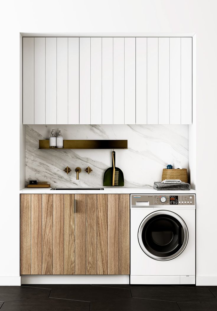 a washer and dryer in a white kitchen with wood cabinetry on the wall